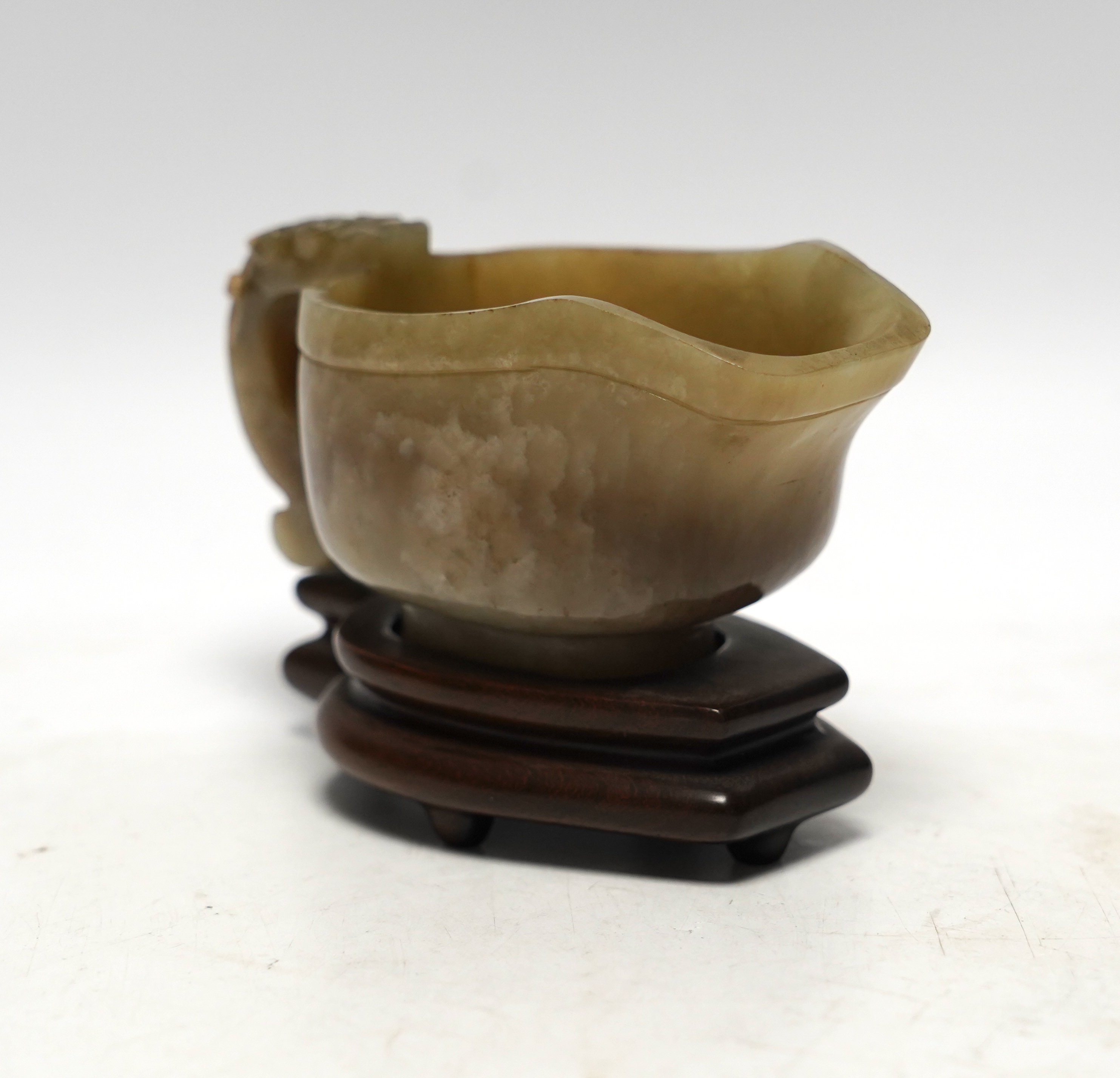 An 18th century Chinese archaistic jade pouring vessel, yi, with carved dragon handle, 6cm high, on a hardwood stand